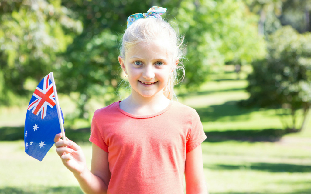 Little girl waving an Australian flag in a park