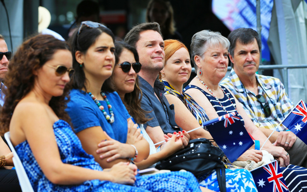 People holding flags sitting in a row watching the stage