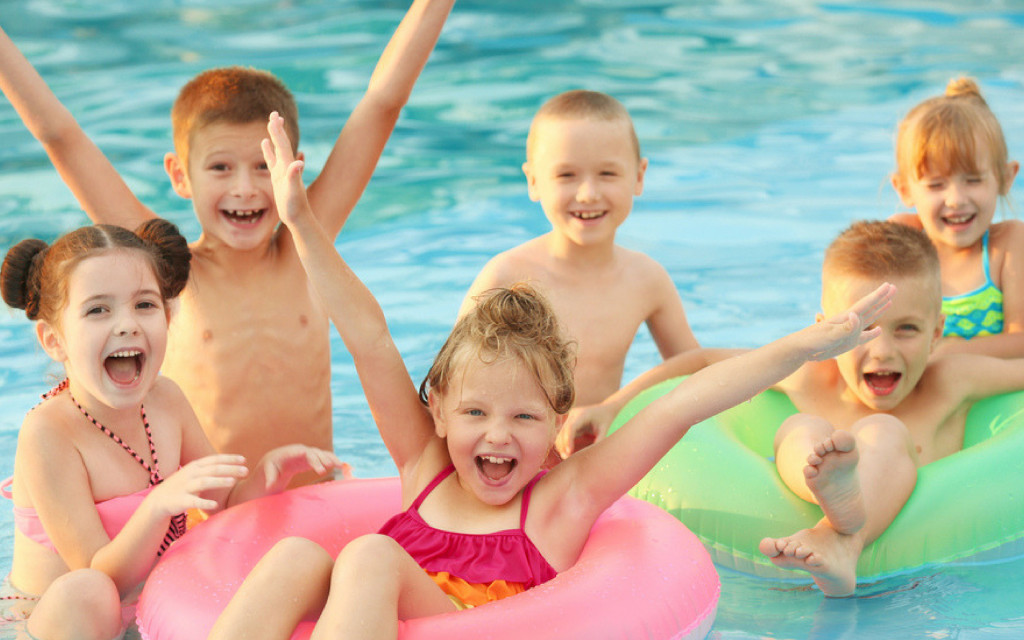 Six happy kids in a pool with two floating donuts