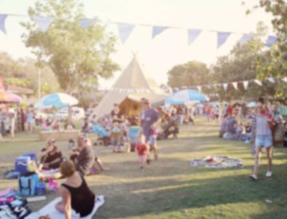 people having a picnic and walking around during a festival in a park